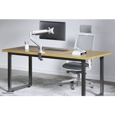 A modern desk with a wooden top, monitor mount, and ergonomic chair on a carpet. Office supplies are on the desk.