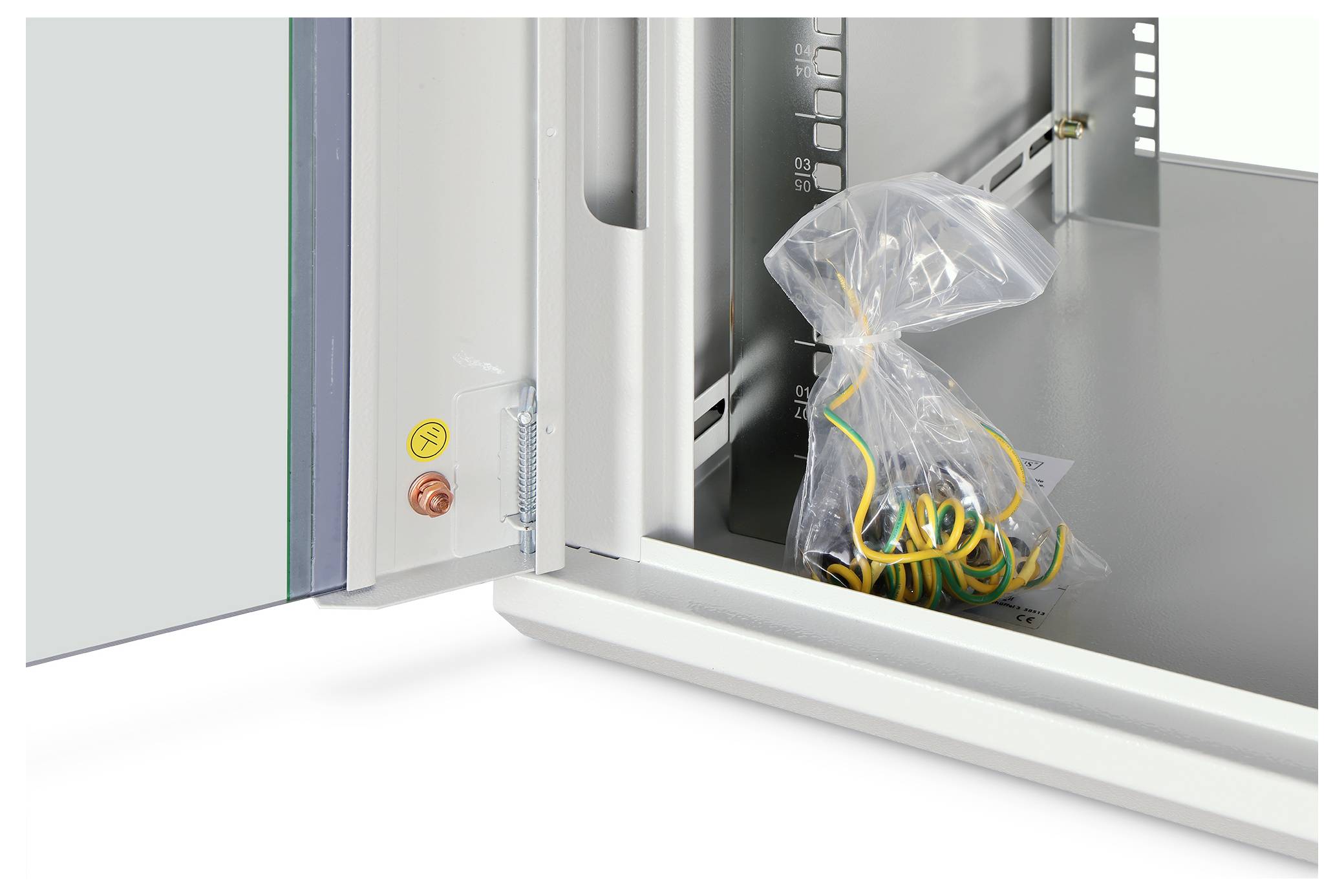 An open metal enclosure shows interior details, including a transparent bag with yellow and green wires on the base. The door is ajar.