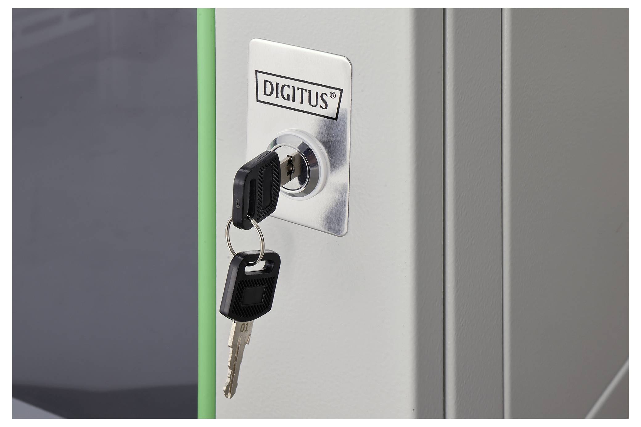 A key inserted in a lock cylinder labeled 'Digitus', with an additional key on the keychain, on a silver metal background.