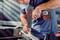 A man is using a cordless drill to turn a screw into a piece of wood in a workshop environment.