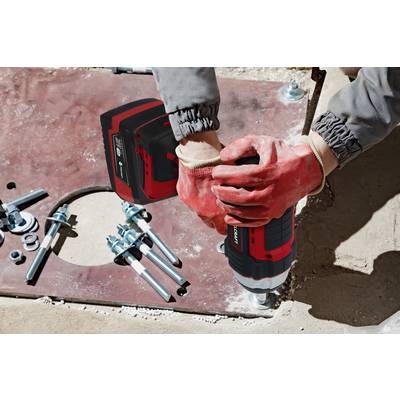 A person wearing red gloves is holding a cordless drill and drilling holes into a metal plate, with screws and nuts lying nearby.