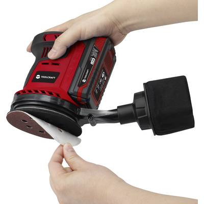 A person is changing the sandpaper on a red, portable electric sanding device with a black dust bag.
