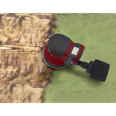 A red orbital sander is sanding a piece of wooden board. On the left, the wood is smooth, while the right side retains the green-painted surface.