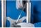 'Close-up of hands wearing gloves filing metal. Two metal cylinders flank the workpiece being processed.'