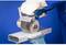 A person is grinding a piece of metal with a grinding machine. They are wearing work gloves; the background is blue.