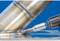 A metal drill is machining a weld seam on a metal joint. The background is blue.