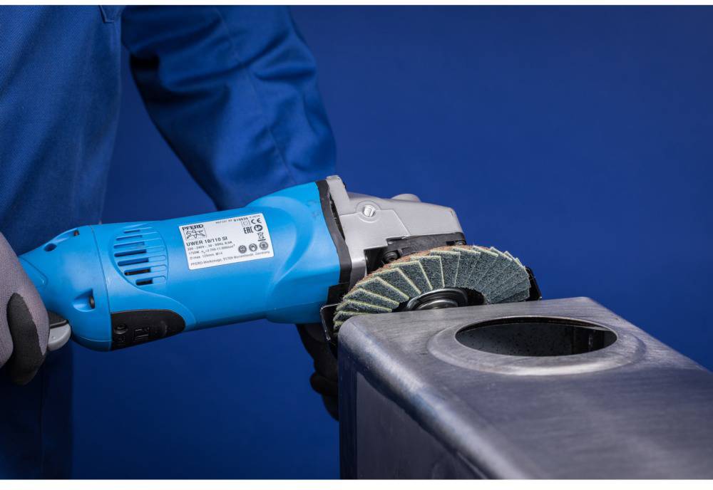 A person is grinding metal with a blue angle grinder. A blue background is visible in the background.