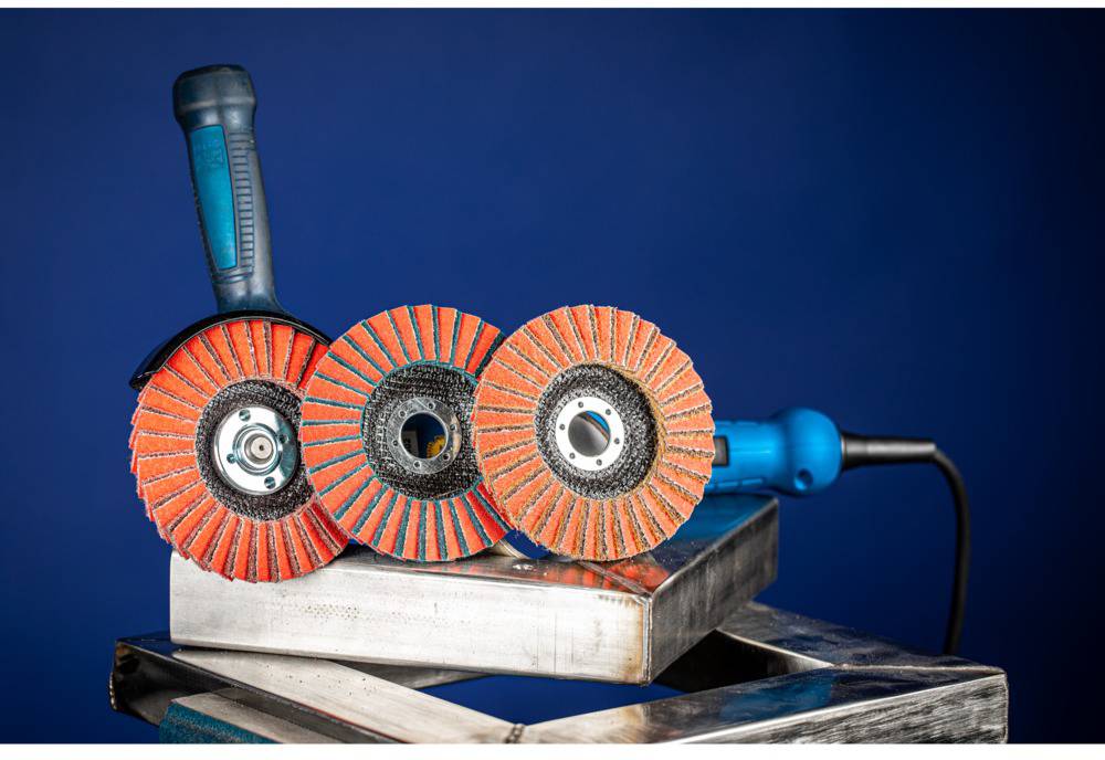 Three red and black grinding discs on a metal block against a blue background. One grinding disc has a blue handle.