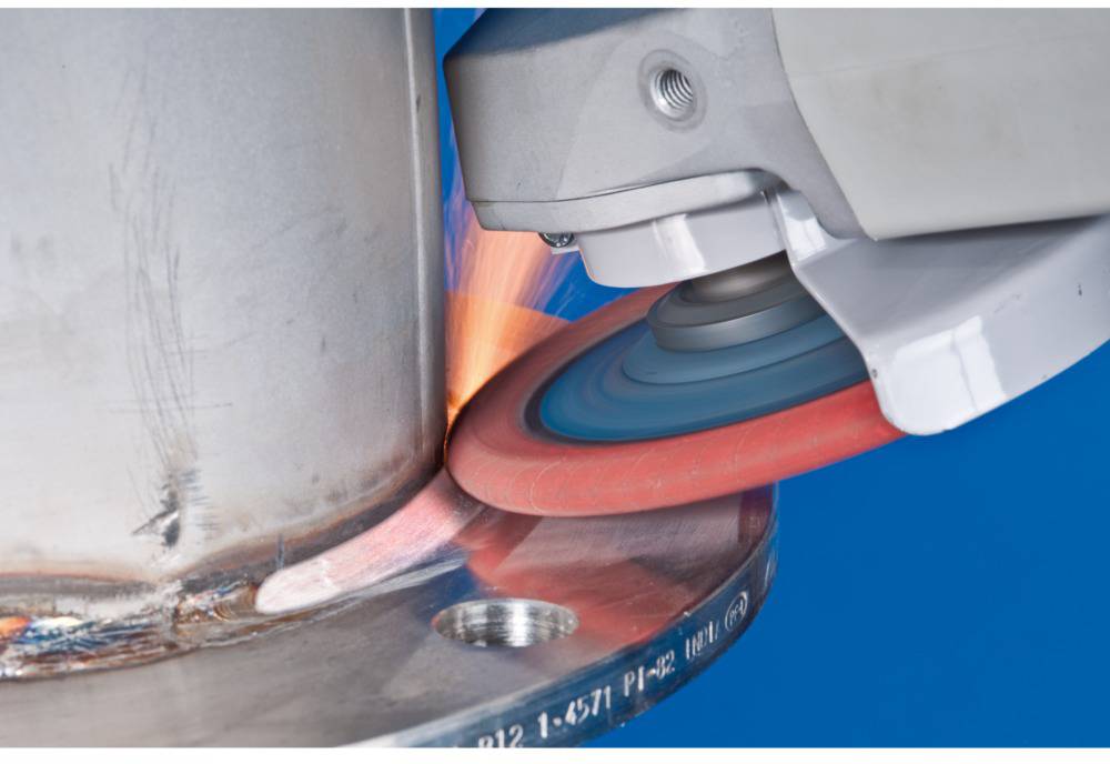 An angle grinder grinds the edge of a metal surface. Sparks are created through the contact of the grinding tool with the metal.