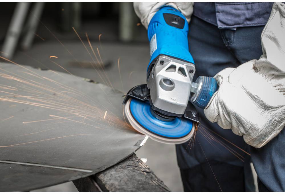 'Person grinding metal plate with angle grinder, sparks flying. Person wearing protective clothing.'