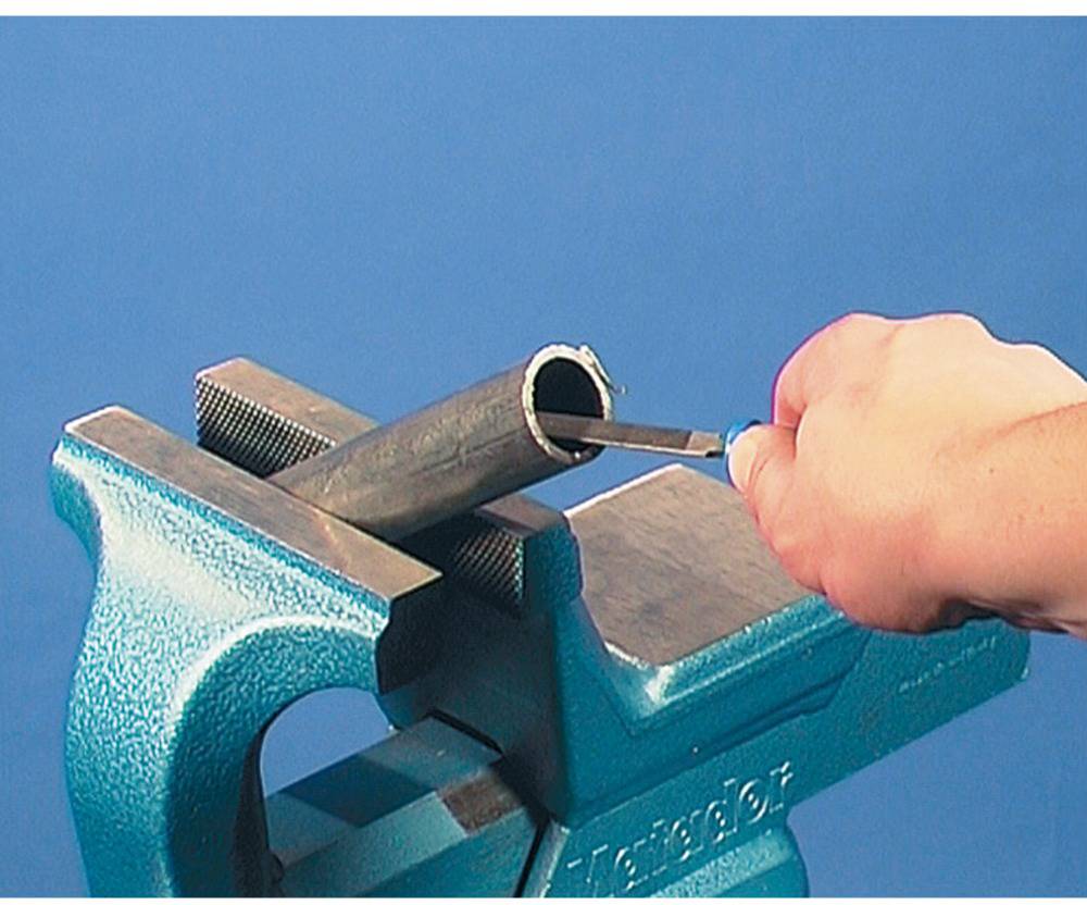 A hand is holding a metal pipe clamped in a vice. A tool is being inserted into the pipe, presumably for cutting or machining.