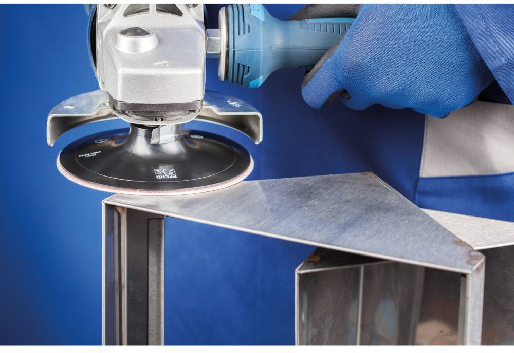 A person is grinding the edge of a metal piece with an electrically powered angle grinder.