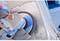 A person is grinding a metal surface of a vehicle with an angle grinder to prepare it for repair or painting.