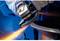 A worker grinds metal with an angle grinder, sparks flying out. Protective clothing is being worn.