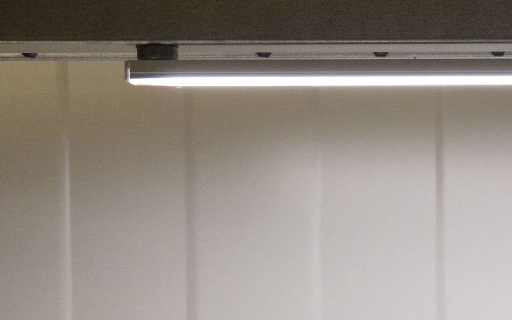 A brightly illuminated ceiling light illuminates a room with white walls. The light source radiates evenly downwards.