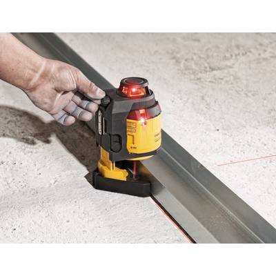 A hand is holding a yellow laser device that projects horizontal red laser lines along a metal rail on a concrete floor.