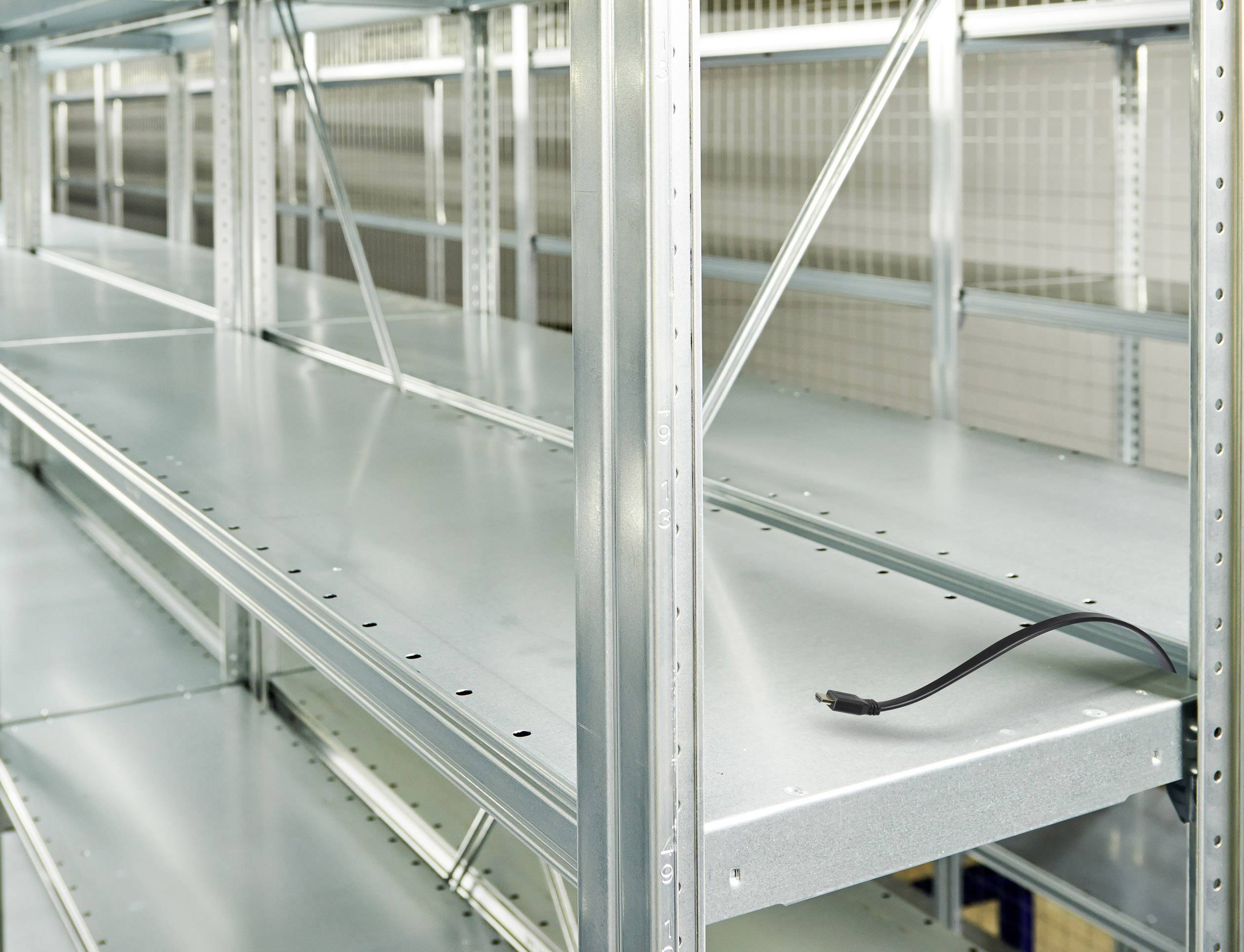 Empty metal shelving unit with a single cable lying loosely on one of the shelves.