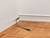 A single black HDMI cable protrudes from the wall with a white skirting board and rests on a parquet floor.