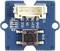 A blue electronic module with a small central black button, various connectors, and labelled pins.