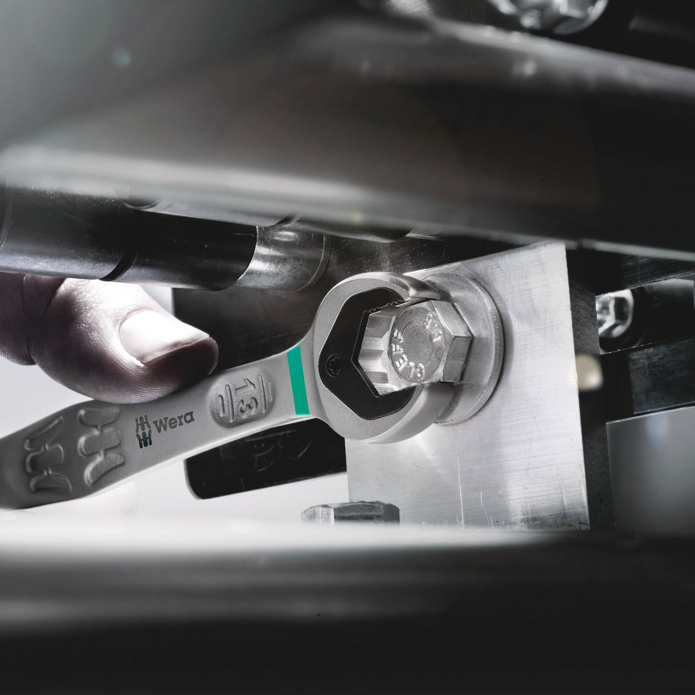 A spanner is used to tighten a screw in a machine. One hand holds the spanner securely.