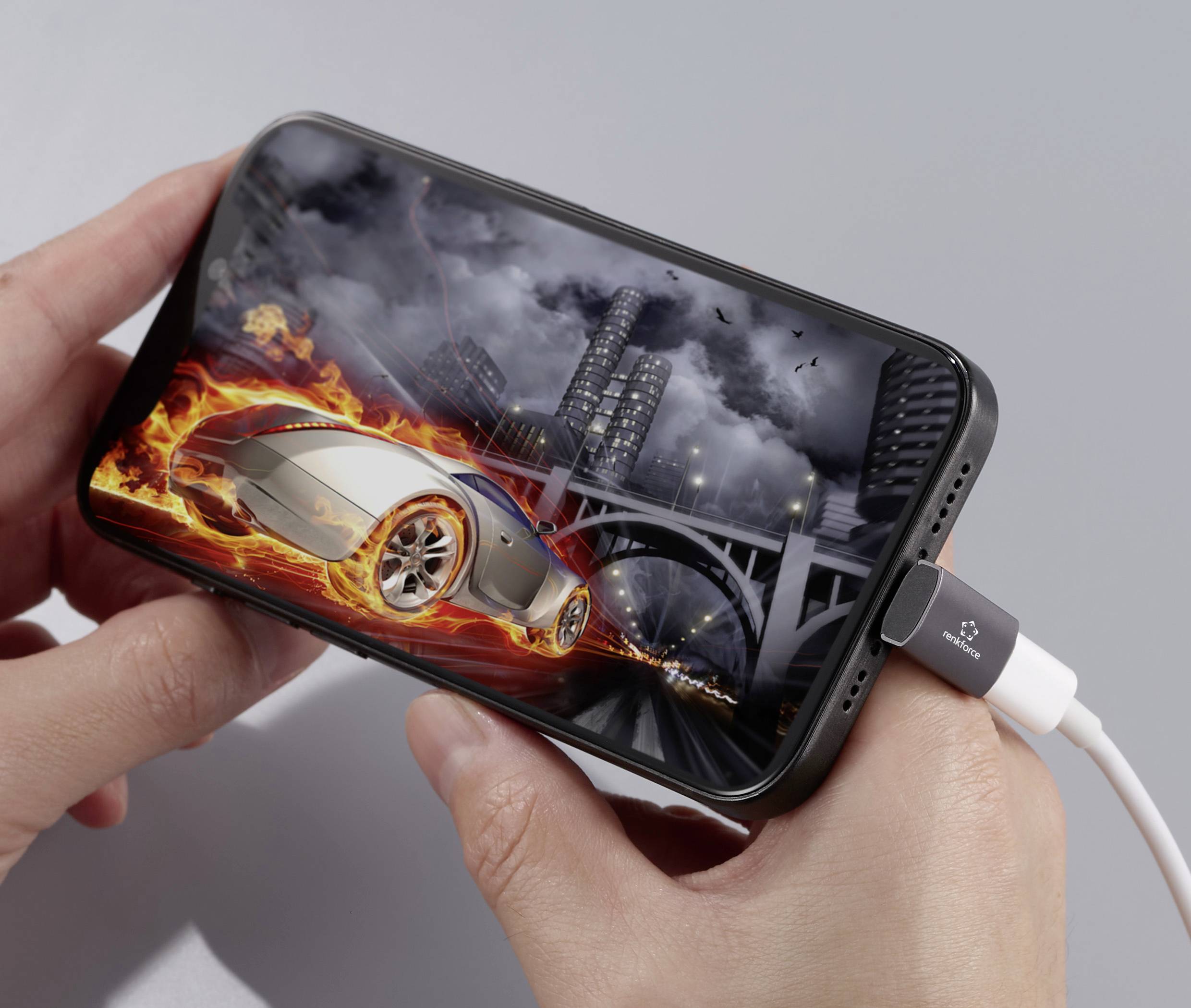 A person is holding a smartphone with a racing game on the screen. The car on it is silver and surrounded by flames.