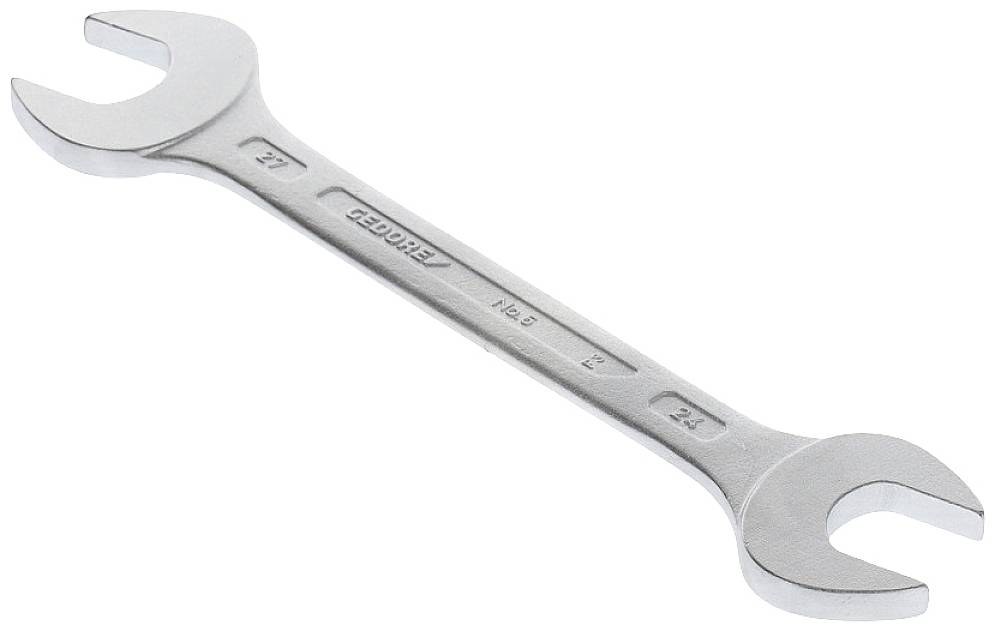 A silver double-ended spanner with sizes 21 and 23, lying on a light surface.