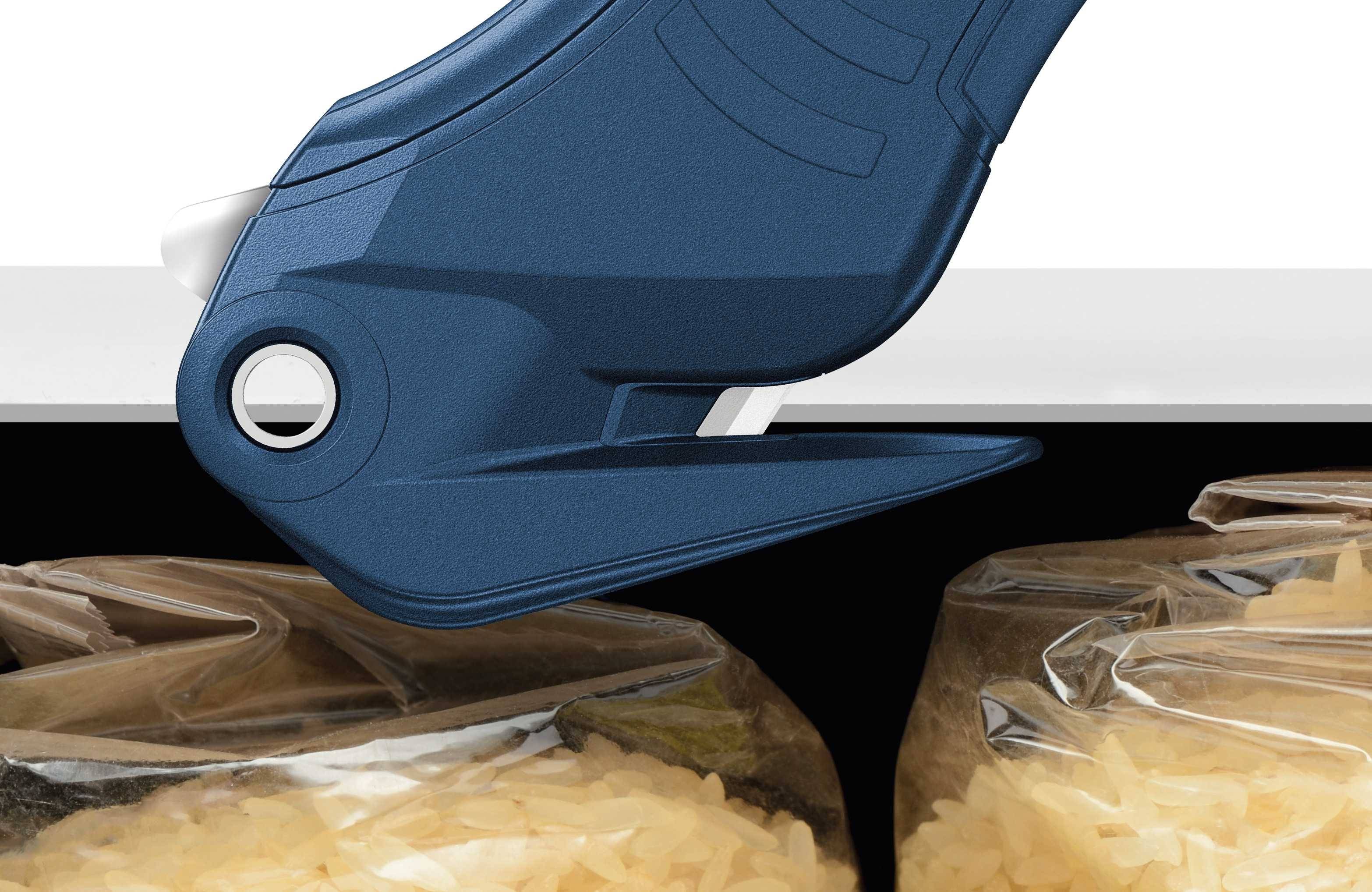 A blue heat sealer cuts the top of a plastic bag containing rice.