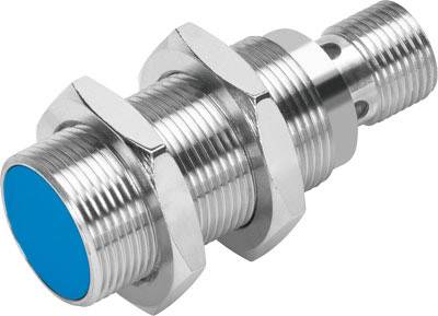 Cylindrical metal induction sensor with a blue plastic cap, threads and nuts for mounting, used for object detection.