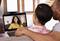 A couple are sitting on a sofa and having a video call via a laptop with a smiling woman in a yellow top on the screen.