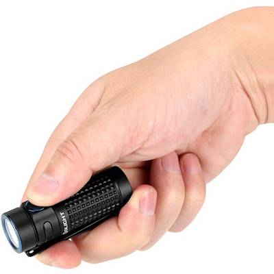 A hand is holding a small, black torch with a textured grip. The torch is switched on and illuminating.