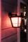Exterior wall light illuminates wall in soft red. Lamp design modern, rectangular window reflects light, creating a cosy evening ambience.