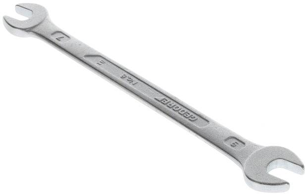 A silver double-ended spanner with size markings 9 and 7, lies diagonally on a white surface.