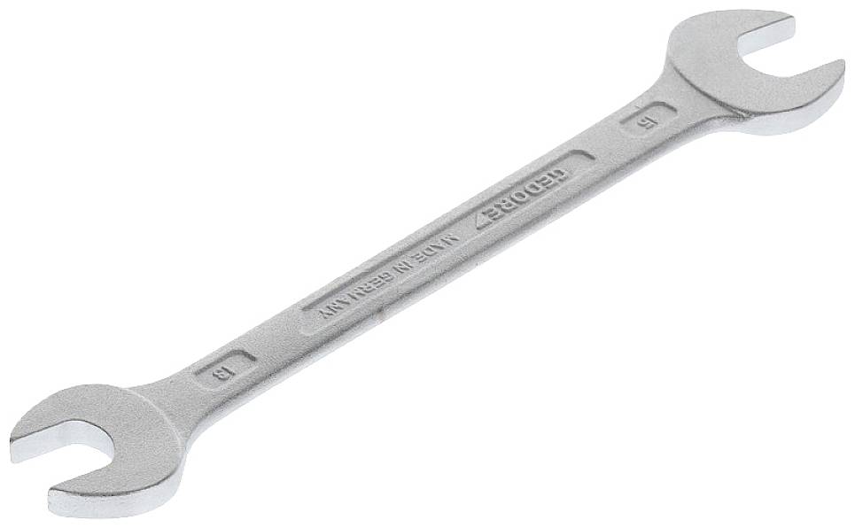 A silver double-ended spanner with sizes 6 and 7 mm, lies at an angle on a white surface.