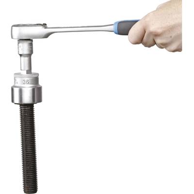 A hand is holding a ratchet that is turning a large screw.