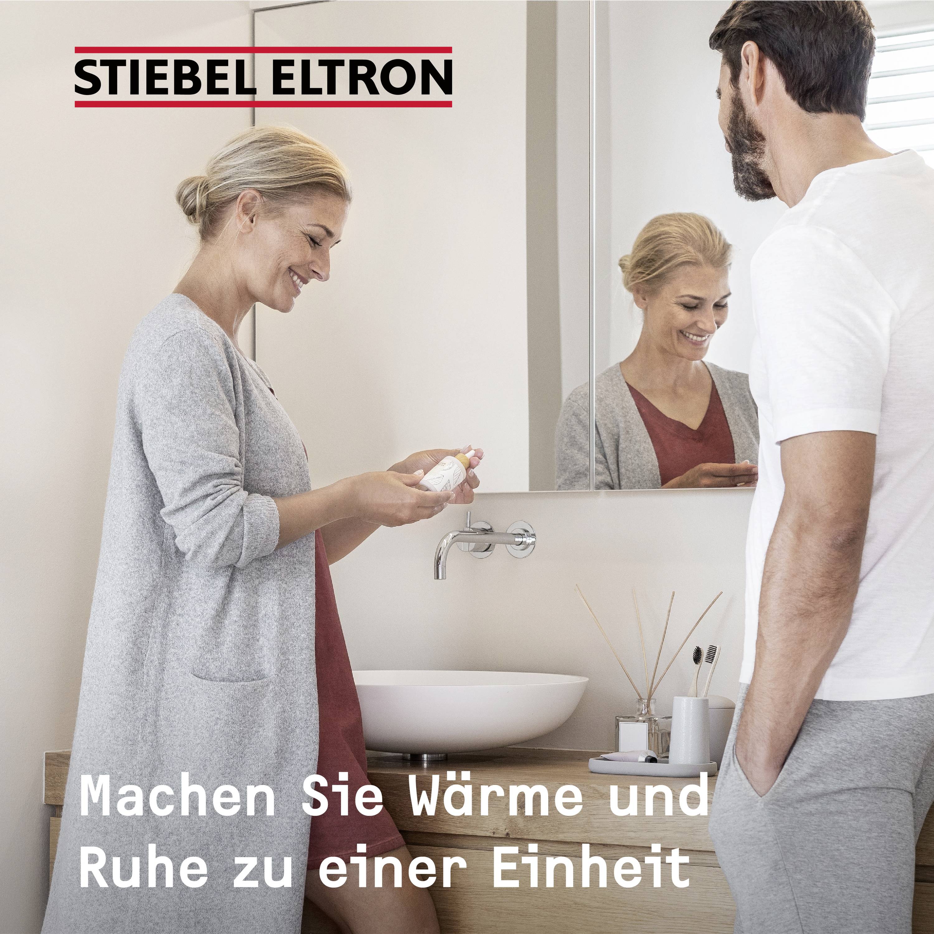 A woman and a man are standing smiling in the bathroom; the woman is holding a cream jar in her hand. Text: 'Make warmth and calm a unity'.