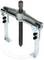 A silver-coloured puller with two arms and a central screw, used for extracting tightly fitted parts from shafts.