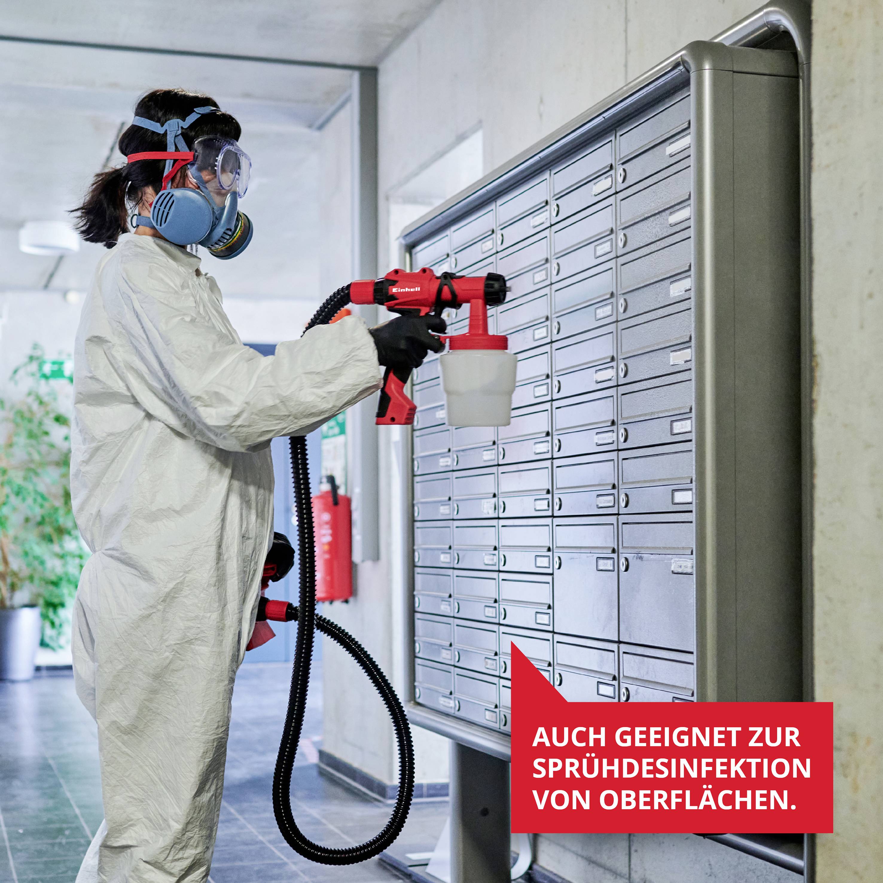 A person in protective clothing is using a spray device to disinfect surfaces. A sign shows: 'Also suitable for spray disinfection of surfaces'.