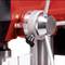 Close-up of a red drill showing the adjustable measuring instrument and metal handle.