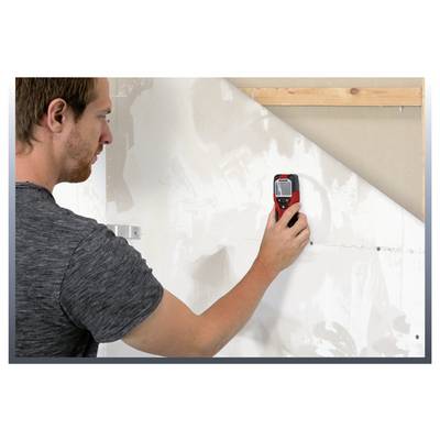 Man using a handheld laser distance meter to measure a wall during home renovation.<br>