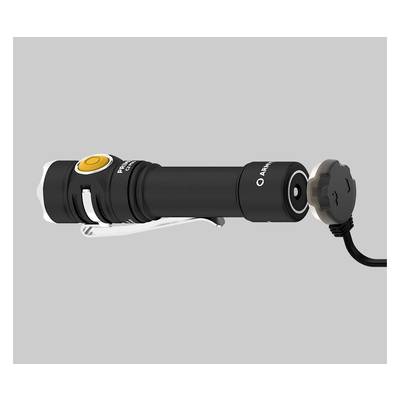 Black torch with a yellow button and metal clip lies horizontally. A round charger is connected to the rear.