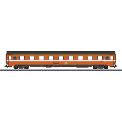 A long, orange railway carriage stands on a track. The carriage has several windows and a narrow white line running along its side.