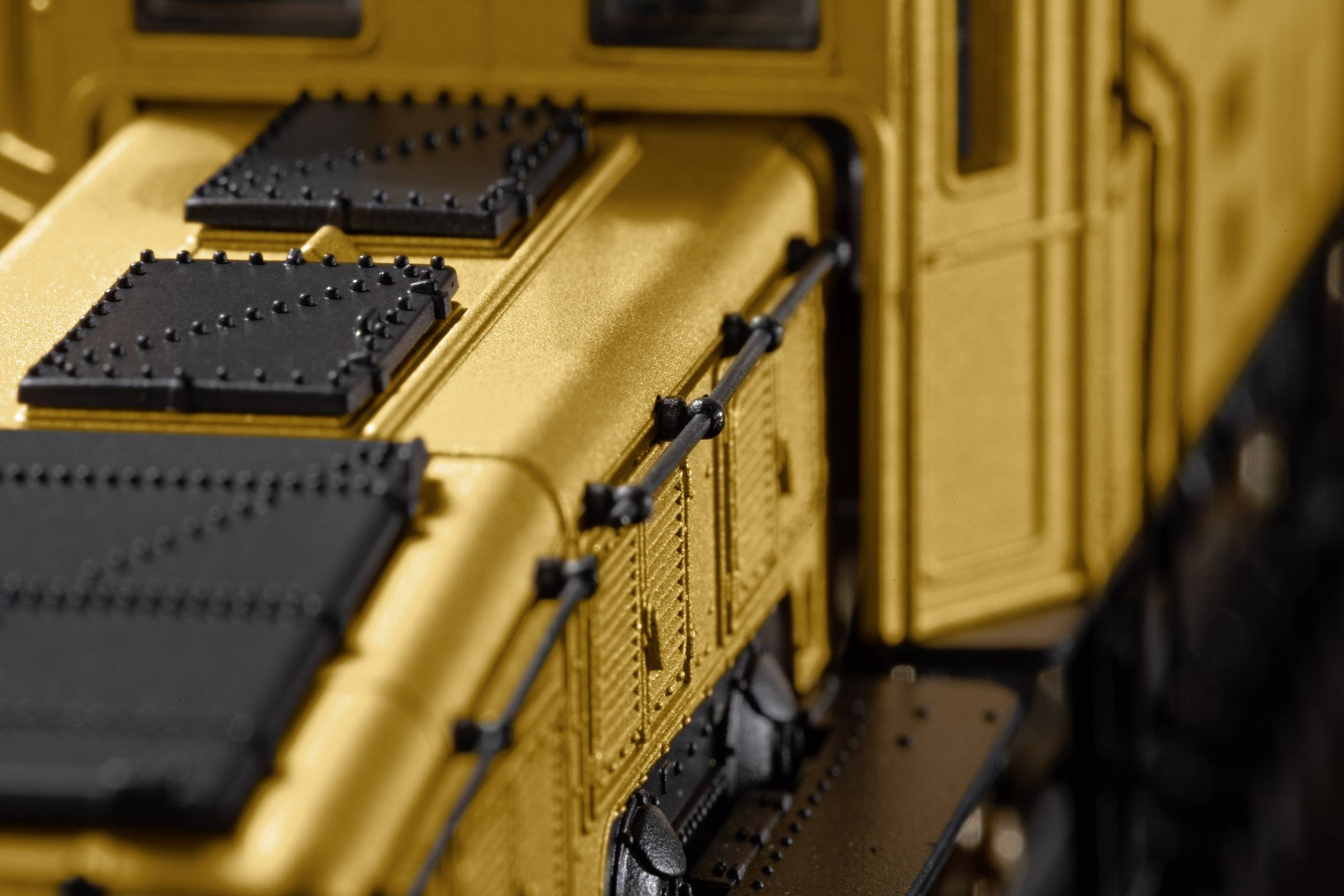 Close-up of a yellow model train with details of rails and windows.