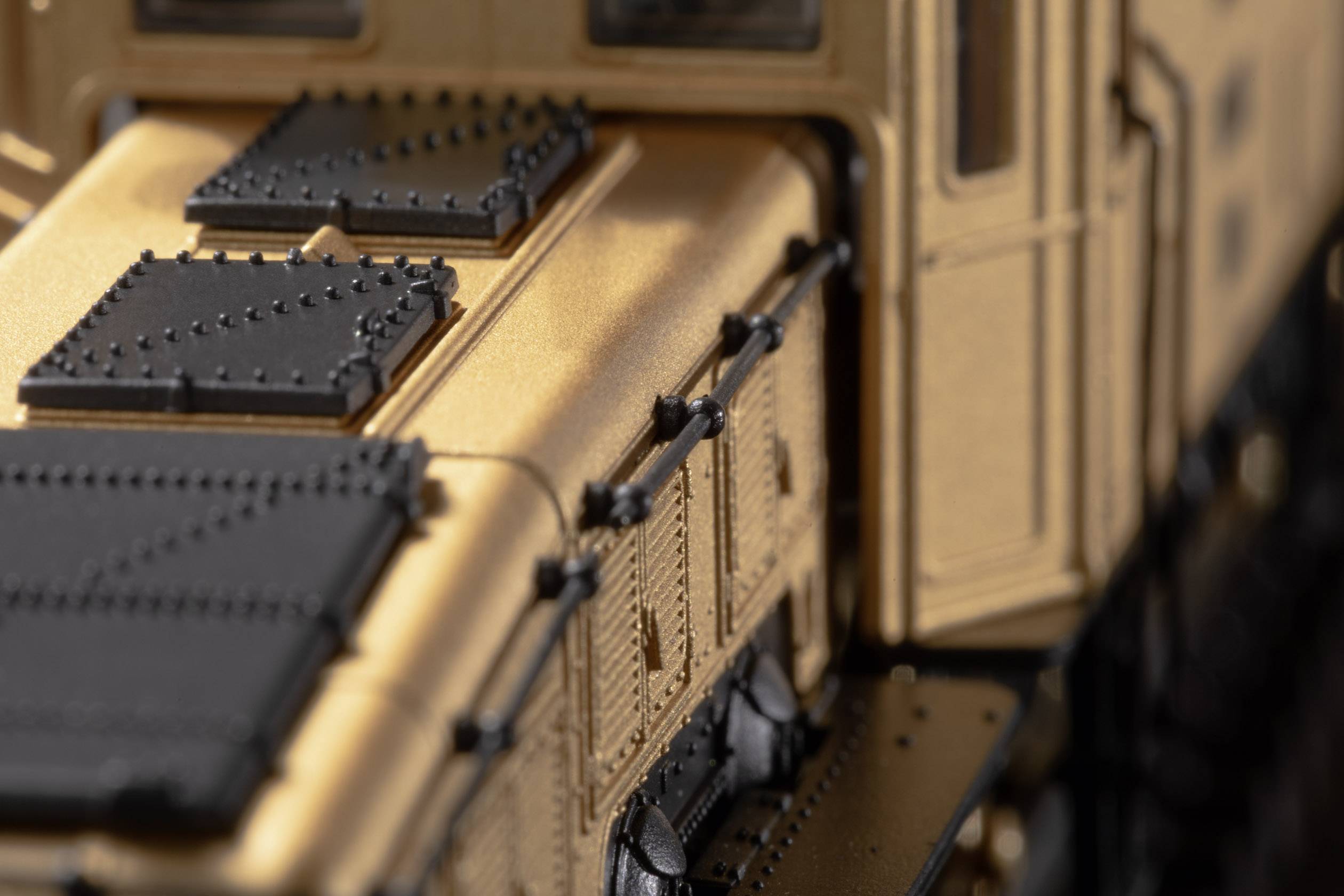 Close-up of a gold-coloured model train carriage with black details, showing the surface texture and mechanics of the carriage.
