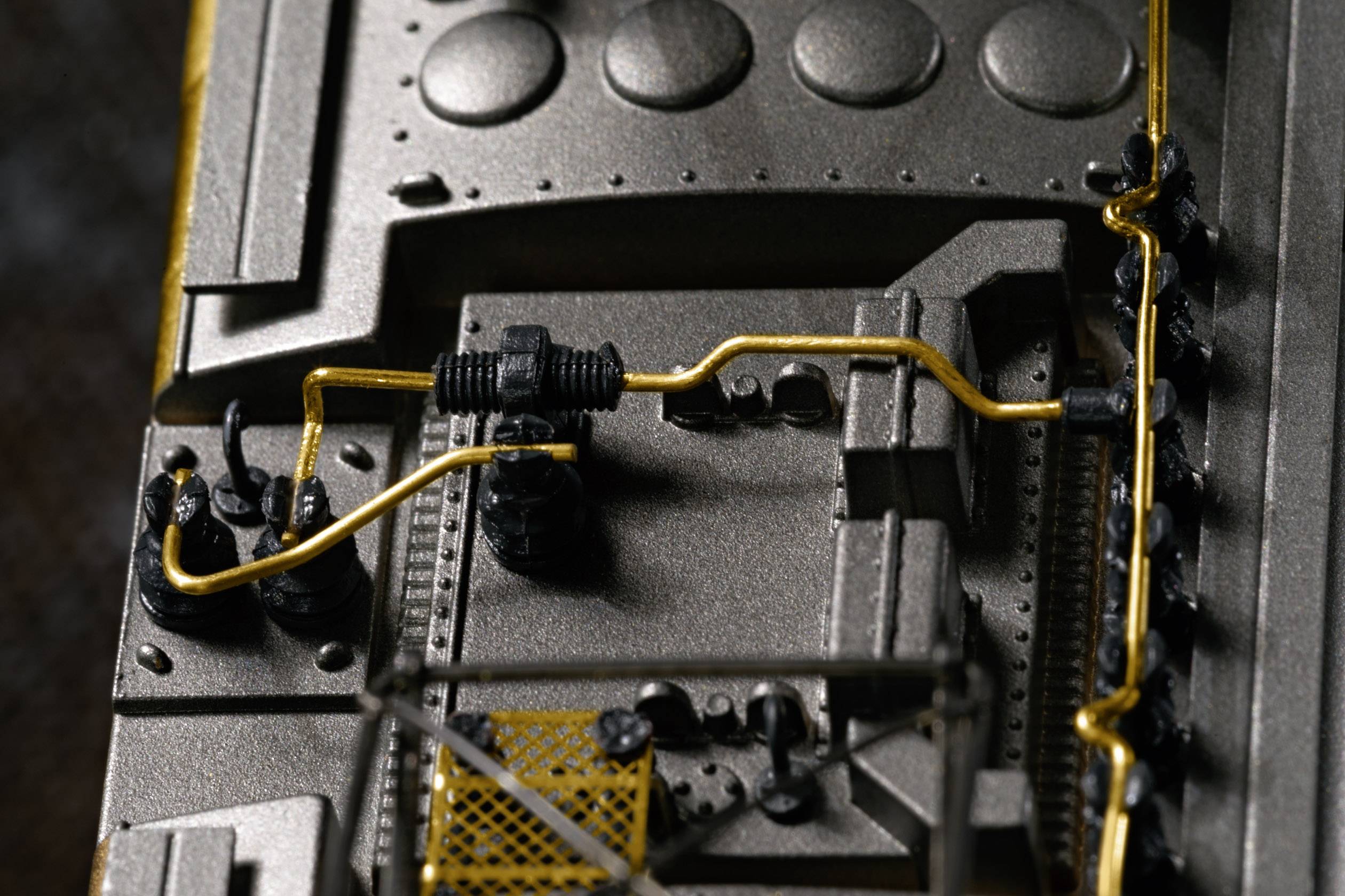 Close-up of a technical device with intricate metal structures and yellow cables on a surface.