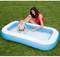 A woman in a red top is playing with a toddler who is sitting in the water in a blue inflatable children's paddling pool in the garden.