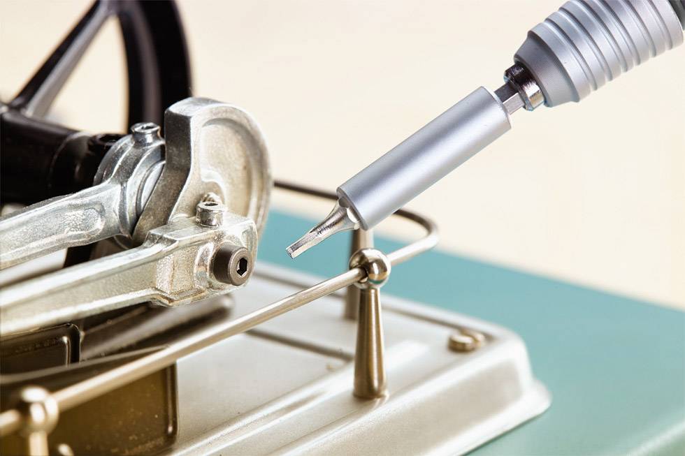 Close-up of a metal arm with a pen that is part of a mechanical device on a green table.开奖现场