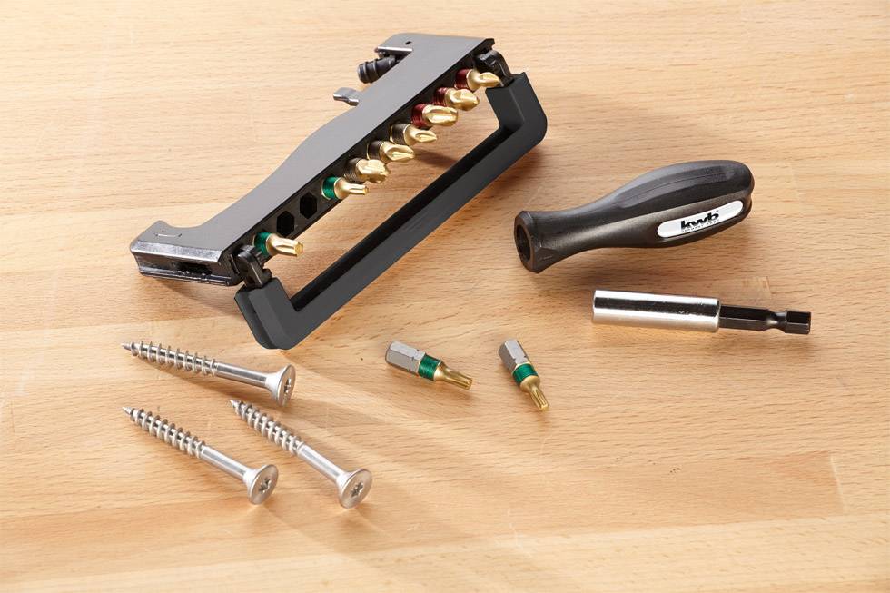 Tool set on a wooden surface: screwdriver with attachments, screws and other accessories.