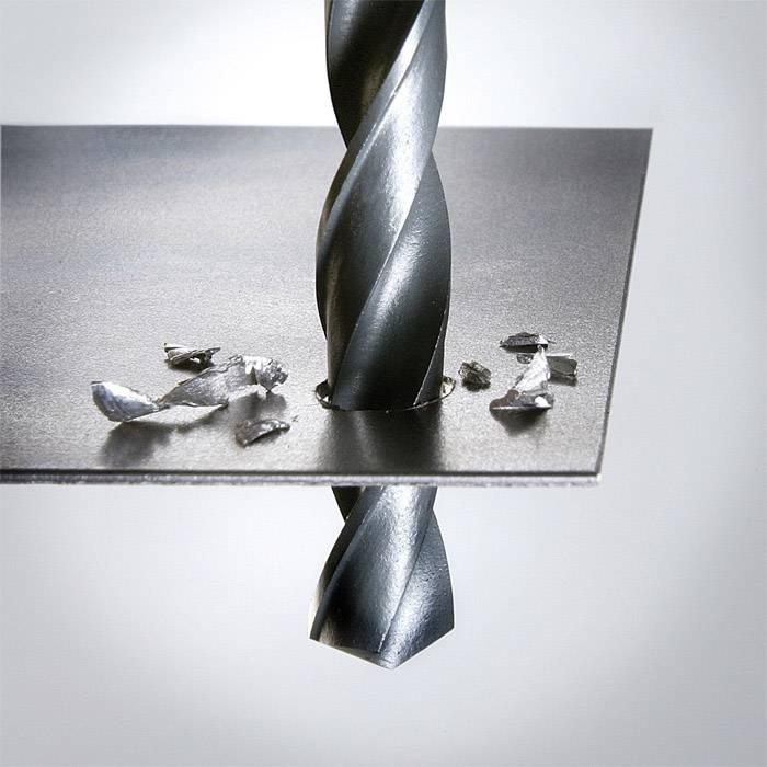 A drill penetrates a metal plate, creating shavings.