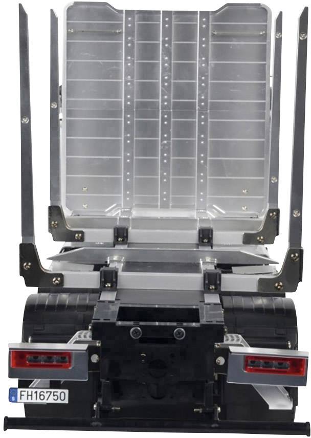 Lorry trailer without cargo, viewed from behind. Paved loading area, empty mountings on the sides, rear lights and number plate visible.