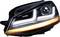 A car headlight with a modern LED design, horizontal white daytime running light strips and an orange indicator beneath.